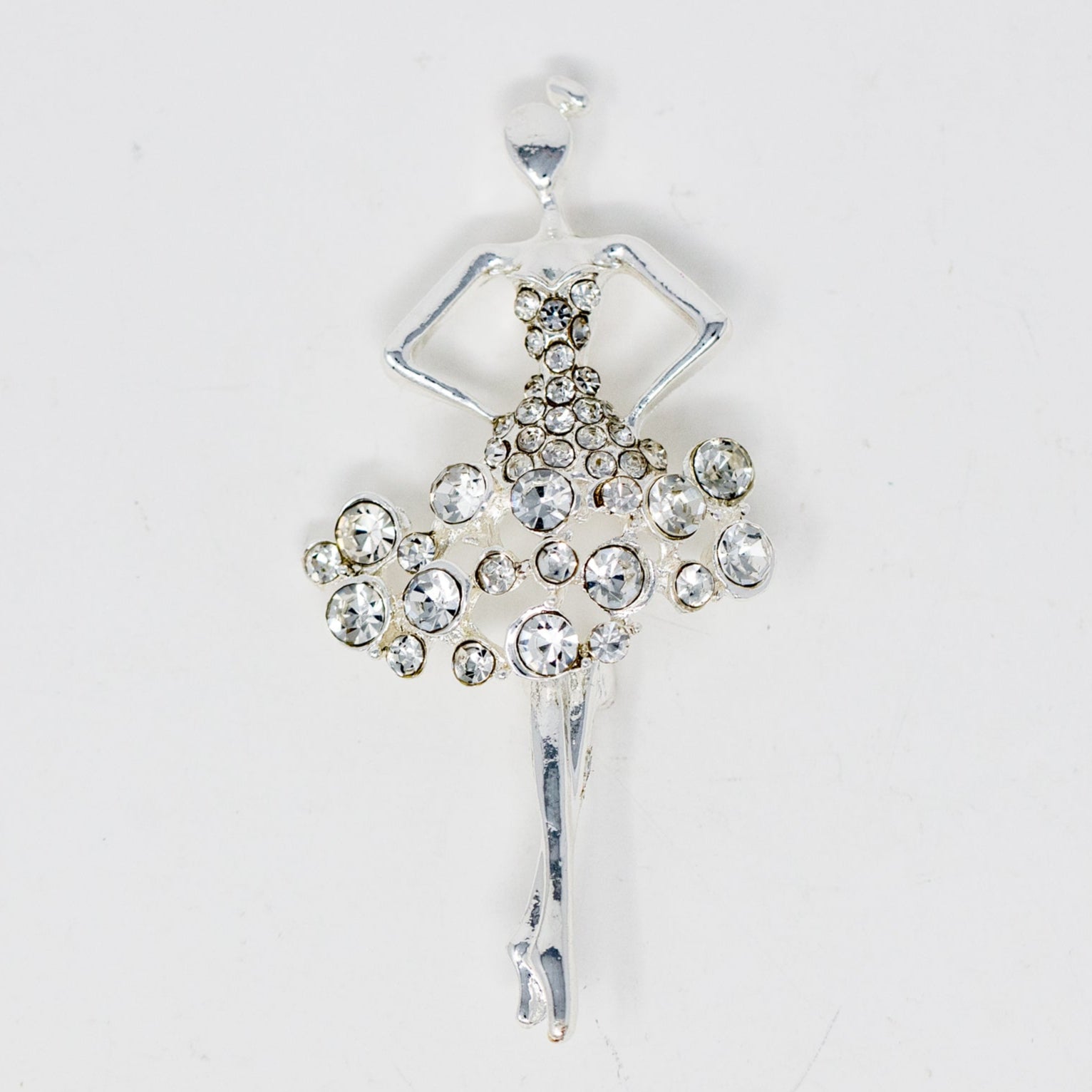 A collectible pin featuring a silver-colored ballerina figure adorned with rhinestones.